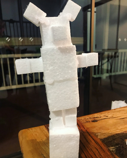 A sculpture of a polystyrene bear held together by glue and sticky tape sitting on a wooden table.