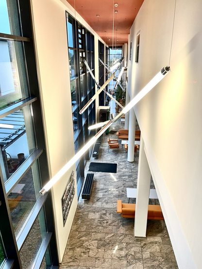 Blick hinunter in die Empfangshalle eines Krankenhauses. Neonlichtröhren bilden geometrische Muster