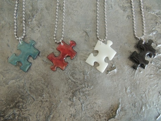Puzzleteile aus Resin in blau, rosa, weiß und schwarz mit einer Kugelkette.