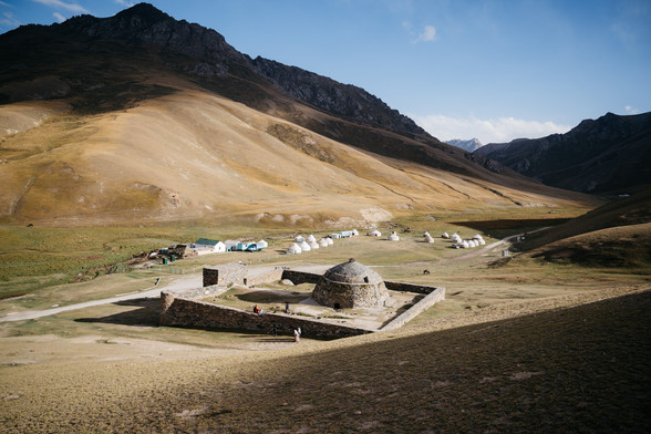 Estructura con muros cuadrados y una cúpula central, situada junto a un camino entre las montañas.
