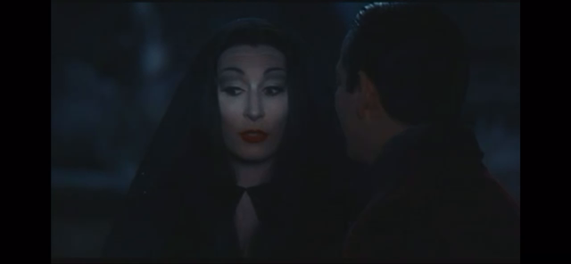 A video clip from “Addams family values“ with Morticia and Gomez, sitting in the dark in a cemetery with Morticia (a pale woman with long black hair) saying “I wish I had more time to seek out the dark forces and join their hellish crusade, that’s all“
With an ending flicker of her eyelashes and coquettish look at Gomez