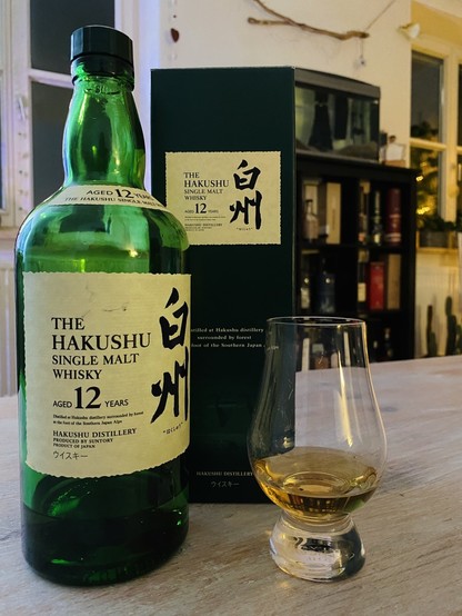 Green bottle of Hakushu with japanese letters on it. Green Cardbox behind it. 