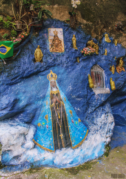 Our Lady of Aparecida ("Our Lady revealed"), (Portuguese: Nossa Senhora Aparecida or Portuguese: Nossa Senhora da Conceição Aparecida) painted on a prominent rock coming out from a hillside in Gloria, Rio de Janeiro. The rock is painted blue and golden Catholic saints and Christ statues painted in gold are accompanying the Virgin.