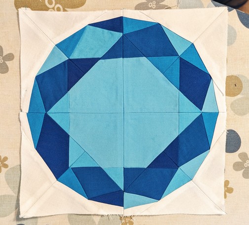 A quilt block featuring a faceted round gemstone.