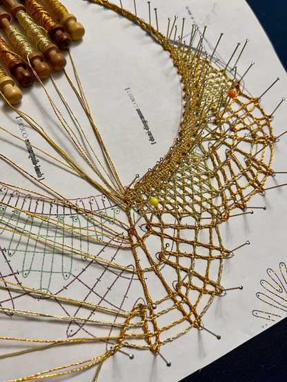 Bobbin lace in progress, with gold colored thread.