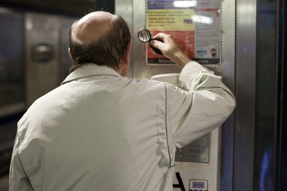 middle-aged friendly: photograph of a balding man trying to read a notice using a magnifying glass. Photo attribution: Flickr user philippeleroyer