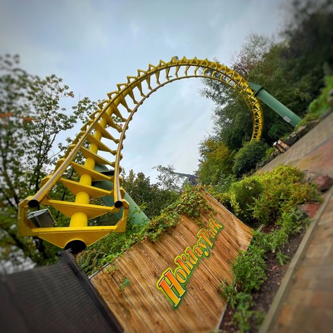 Photo of one of the yellow corkscrew elements from the removed Super Wirbel roller coaster, left as a monument over a path at Holiday Park, Germany. 