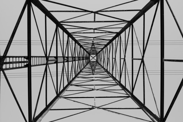 Digital Black and White photo of Pylon/high tension tower looking up from the center of the base