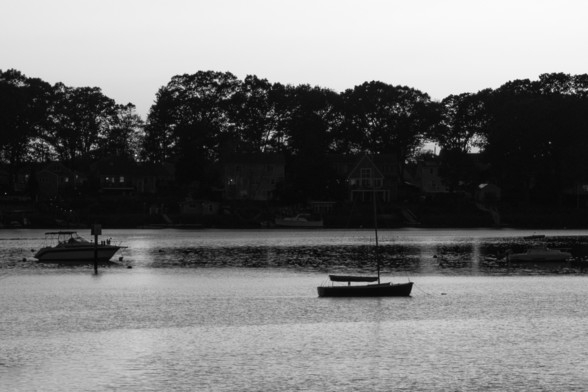 Boats on moorings in the cove, just after sunset in black and white