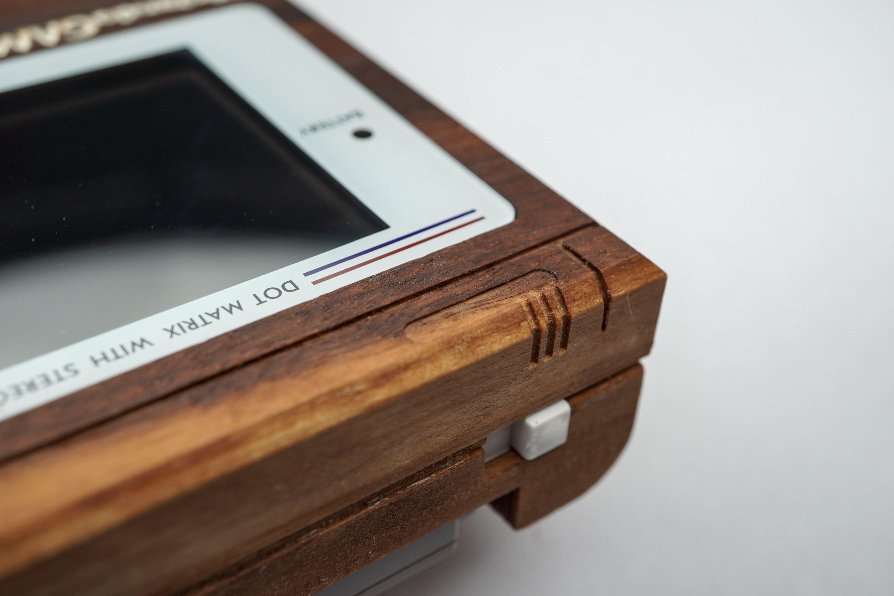 Detail shot of the power switch at the top of the wooden Game Boy. The shot also shows the white screen bezel and the detailed decorative lines that are part of the recognizable design of the original Game Boy.