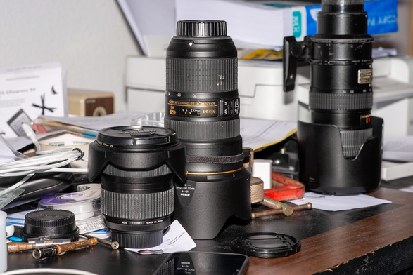 Messy desk in disarray with camera lenses in photo