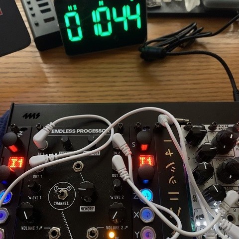 A small #Eurorack modular sample player and signal processor on a table. A nearby timer clock shows an elapsed time of 10 minutes and 44 seconds.