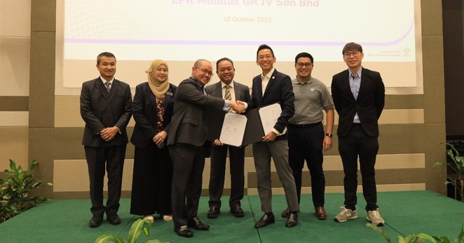 A group of people on a stage exchanging agreement.