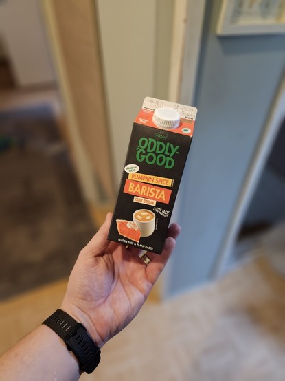 Kädessä OddlyGood Pumpkin Spice Barista kaurajuoma.