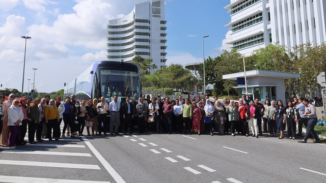 A group of people posing for group photo in front of ART vehicle.