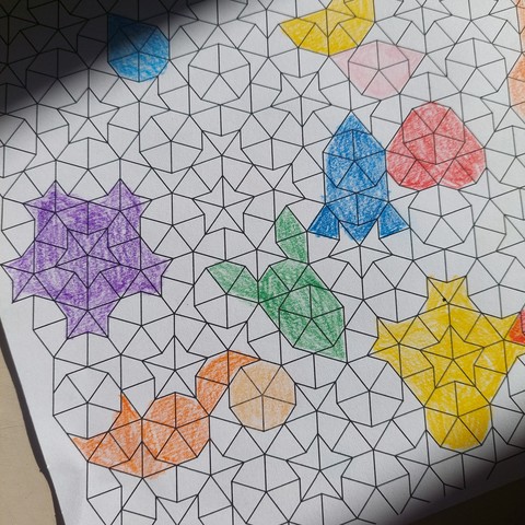 Une feuille blanche couverte d'un pavage aléatoire de Penrose et dans lequel des formes ont été colorées aux crayons de couleurs
