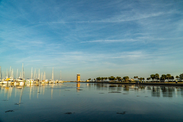 a blue sky over still water with boats on the left.