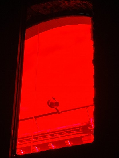 Foto de una ventana desde el interior. Tiene un material translúcido rojo, así que la luz del exterior es roja y el interior está completamente oscuro 