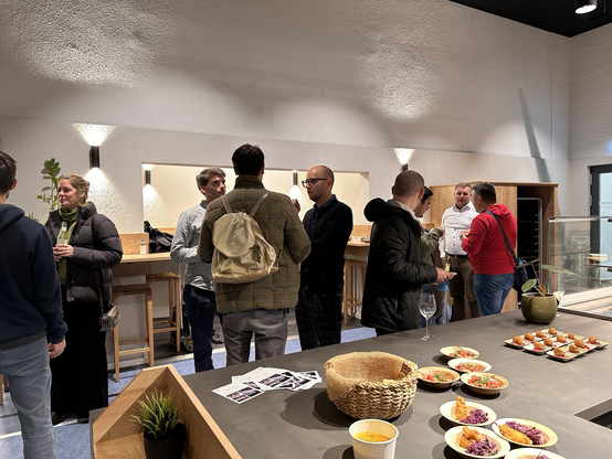 Besucher:innen des World Usability Day stehen in der Cafeteria der Hochschule zusammen und networken.