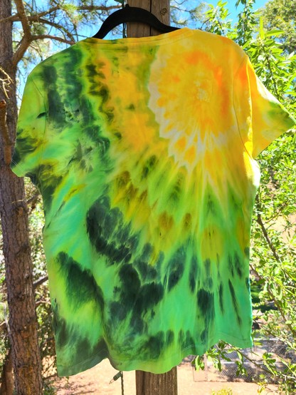 A tie dyed t-shirt with a radiating yellow sunburst flowing down off the shoulder, blending into high contrast greens