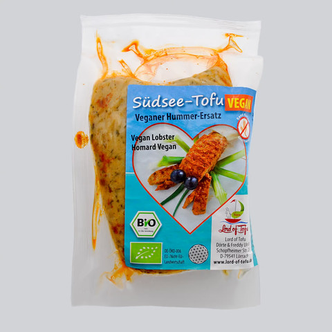 Lord of Tofu Hummer Verpackung, in transparentem Kunststoff eingeschweißtes Stück formloses gewürztes und mariniertes Tofu. Darauf ein Aufkleber mit Beschriftung und sehr speziellem Produktfoto (Details siehe nächstes Bild)