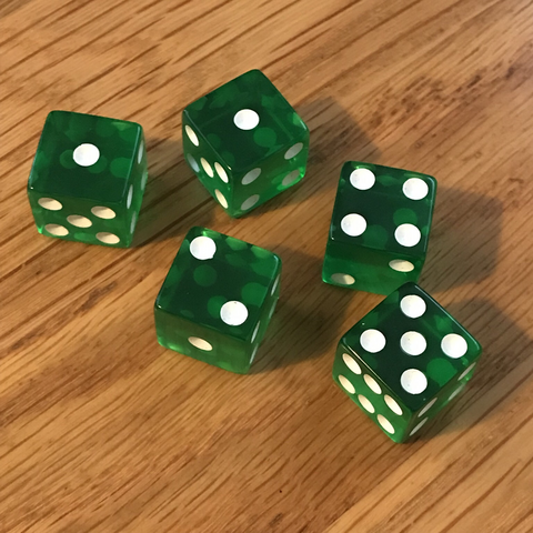 Photograph of five green, translucent plastic dice on a wood desk.