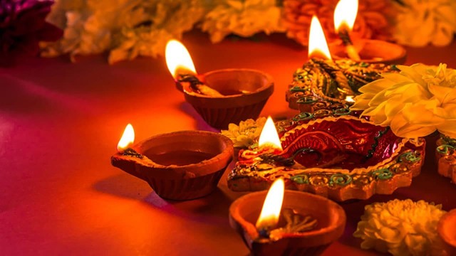 a semi circle of lit diyas (diwali candles) flowers