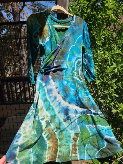 A long sleeved knee length dress that has been dyed to resemble geodes, large organic irregular circular shapes. Many shades of blues, greens, bronzes, with bits of purple 