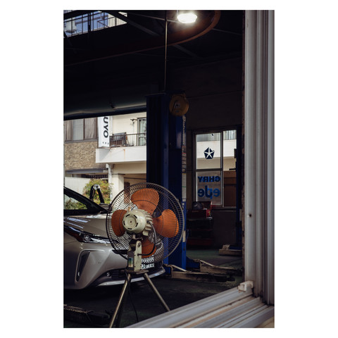 Imagine an auto-garage where the calm is only broken by the occasional clink of a wrench and the soft whirl of a fan. A Chrysler, a rare sight in this city, sits patiently, perhaps pondering its own tales of the roads traveled.