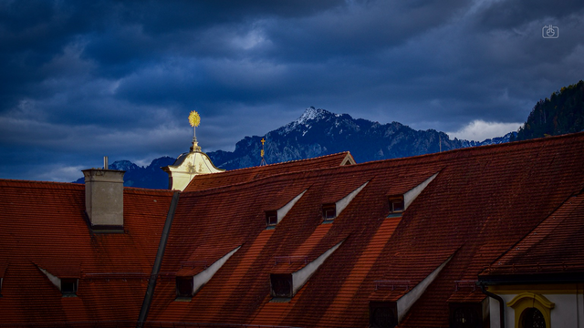 Rooftops of Monastery and Church of St. Mang with a cloudy sky and Alpine mountain peak, Füssen, Allgäu, Bavaria, 11 Nov 2023. Nikon D5600, Nikkor DX 35 mm ƒ1.8G, ISO 100, ƒ4.5, -0.7 ev, 1/2000s
