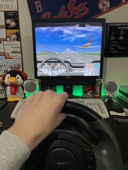 Photo of steering wheel controller being used for Midtown Madness, with the game on screen at Meigs Field