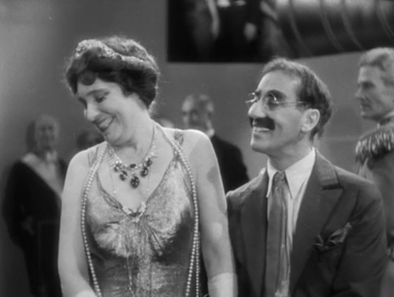 Groucho Marx flirting with his perennial foil, Margaret Dumont. Both are smiling, Margaret is being demure.