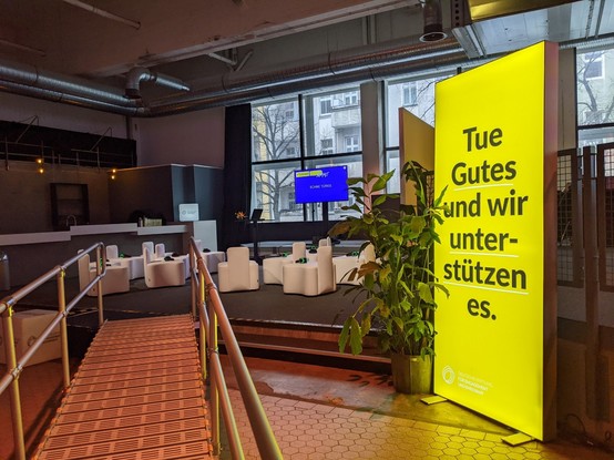 Gesprächsraum mit Leuchtschild "Tue Gutes und wir unterstützen es"