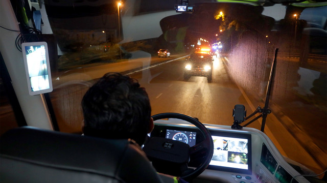 A person sitting on driver seat monitoring various screens as the vehicle moving the other direction.