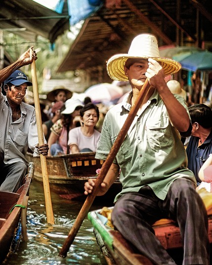 Rowers in Thailand Water Market carry passengers to shop at riverside stalls