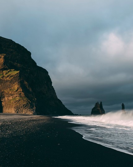 Volcanic sands frame Reynisdrangar's black beach, where basalt columns stand sentinel against the Icelandic waves.