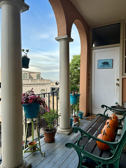 Picture of a small back porch in San Francisco with five pumpkins lined up on a bench.