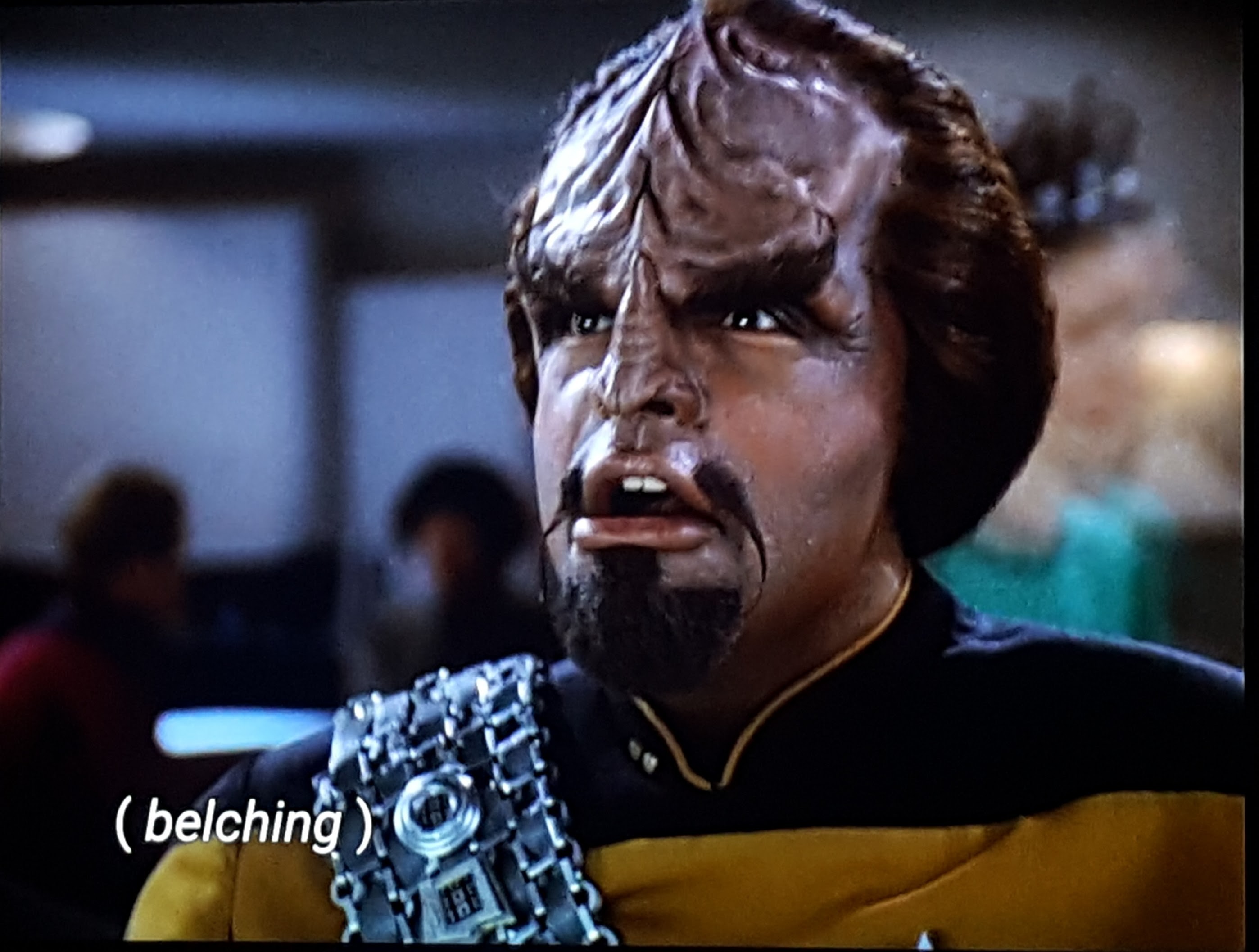 Worf is in Ten Forward, and he's belching. Closed caption reads: (belching)