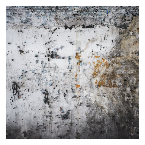 Photo of a wall opposite a platform on the London Tube. Where usually an advertisement can be seen there's a blank wall covered with abstract patterns as a result of peeling layers of paint, paper and mold.