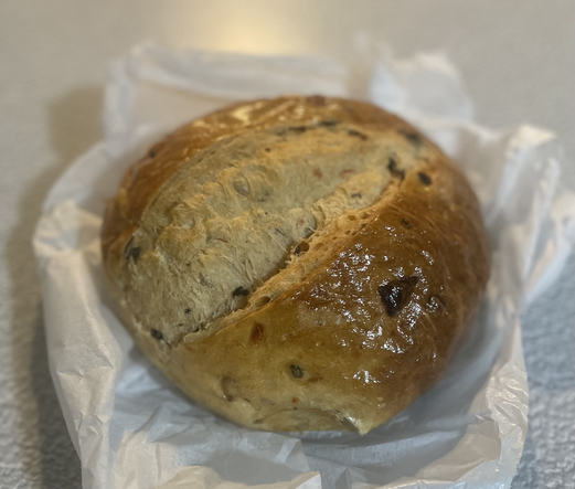 Fresh, round loaf of sundried tomato bread with a glossy crust