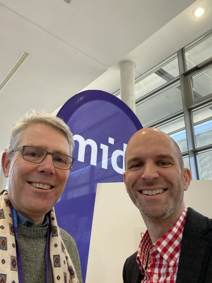 Selfie zwei männliche Personen vor einer violetten Fahne mit der Aufschrift midi