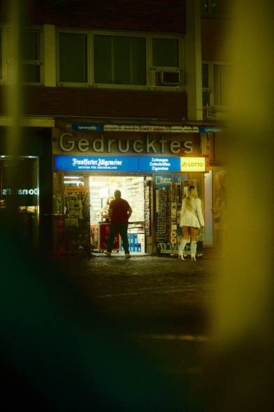 Kiosk mit Menschen und Zeitungsständer bei Nacht 