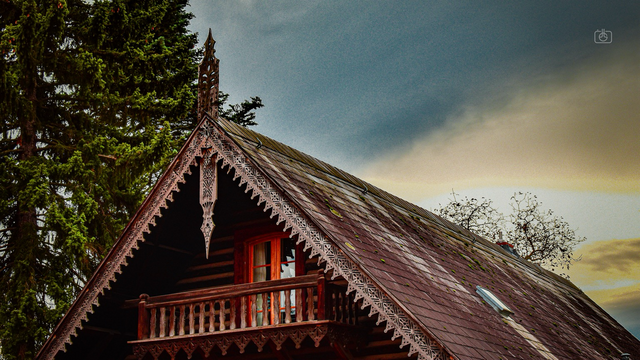 Roofline of Russian cottage against a glowering sky, Alexandrowka (Russian Colony), Potsdam, 2 Nov 2023. Nikon D5600, Nikkor DX 35 mm ƒ1.8G, ISO 100, ƒ9, -0.7 ev, 1/125s