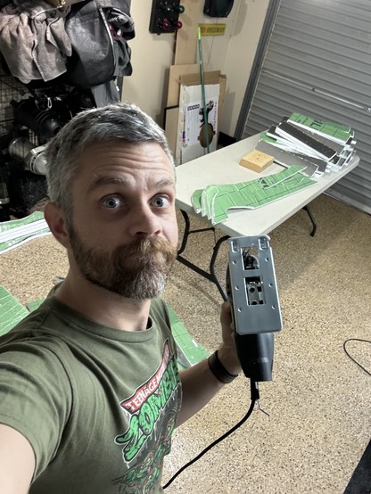 A photo of me holding a jigsaw after cutting out a bunch of foil board pieces
