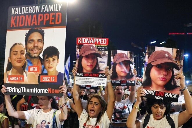 Des soutiens des familles d’otages brandissent des affiches avec les images de la famille Kalderon et de Liri Albag le 11 novembre 2023 à Tel Aviv. © Photo Ahmad Gharabli / AFP