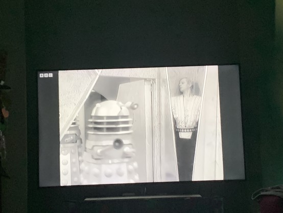 A thal hiding in a tiny recess, daleks to the left