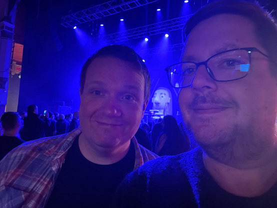Selfie of Robert and Ben in front of the stage with a giant inflatable cartoon head of Daði Freyr in the background