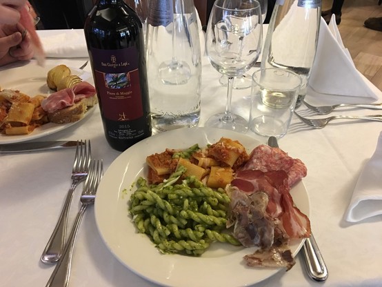 A table with a bottle of wine and a plate full of food