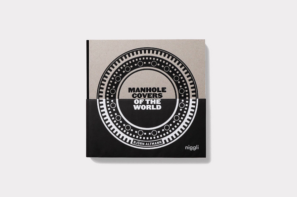 Book cover.
Cover divided in half top in grey and half bottom in black.
Text on center top in black: Manhole Covers.
Text on center bottom in white: Of The World.
The title is surrounded by a patterned border like a manhole with no filled center. On the bottom of the circle: Björn Altmann.
On bottom right in white text:  Niggli 
