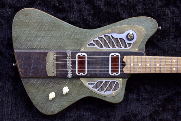 A jauntily shaped electric guitar in a rustic motif, greyish green with a wide, dark brown stripe in the middle, brass and aluminum hardware in an art deco style, and dark red pickup covers, against a black background.